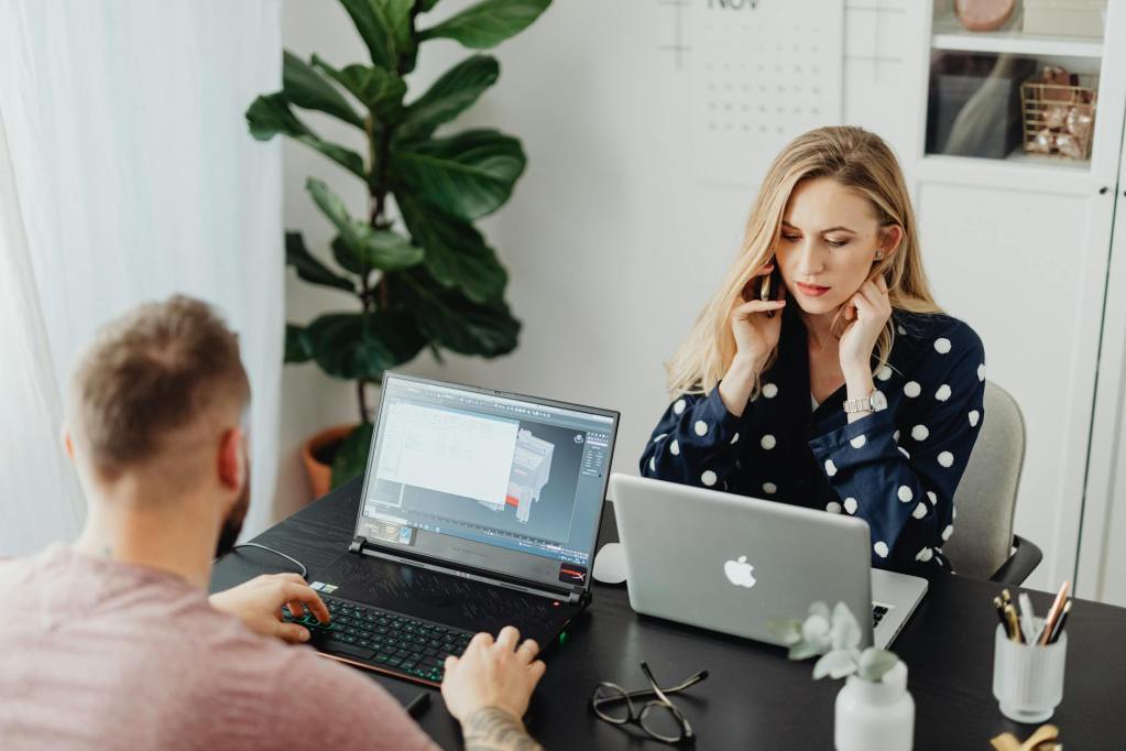 man and woman using laptop while sitting on the table